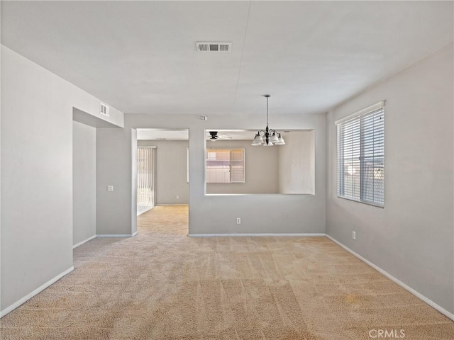 empty room with light carpet and ceiling fan with notable chandelier