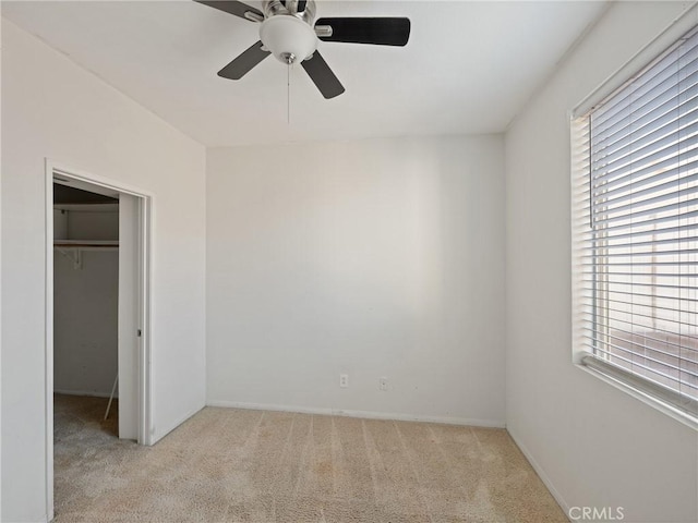 unfurnished bedroom featuring a closet, light colored carpet, a walk in closet, and multiple windows