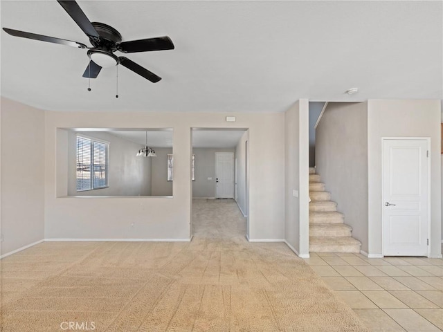 carpeted empty room featuring ceiling fan with notable chandelier