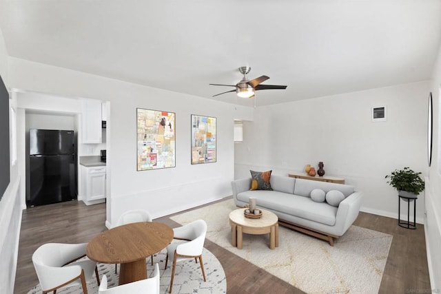 living room with ceiling fan and dark wood-type flooring