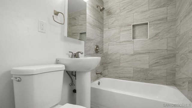 bathroom featuring toilet and tiled shower / bath