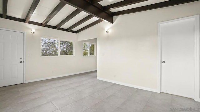 tiled spare room featuring vaulted ceiling with beams