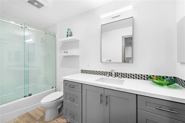 17 Monaco, Newport Beach, CA 92660 - bathroom featuring vanity, toilet, bath / shower combo with glass door, wood finished floors, and decorative backsplash