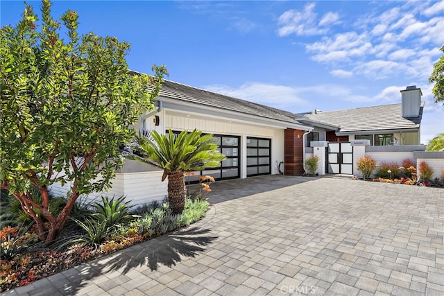 17 Monaco, Newport Beach, CA 92660 - view of front of house featuring a gate, a garage, decorative driveway, and a chimney