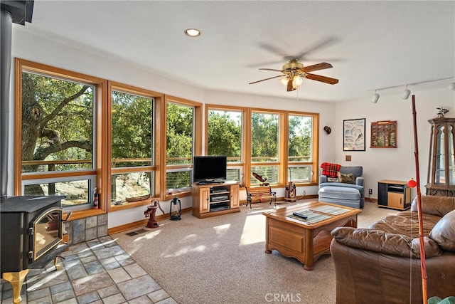 sunroom featuring a wood stove and ceiling fan