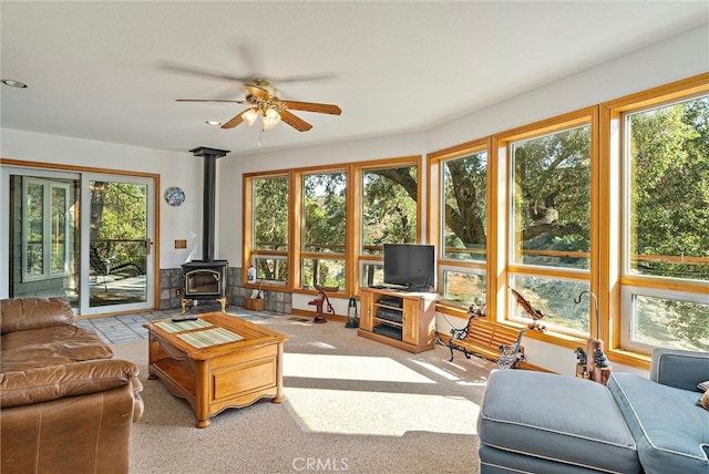 living room featuring ceiling fan, a wood stove, and a wealth of natural light