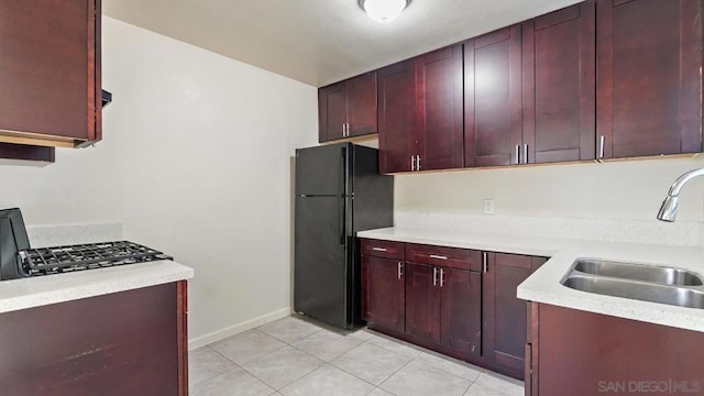 kitchen featuring sink, light tile patterned floors, and black refrigerator