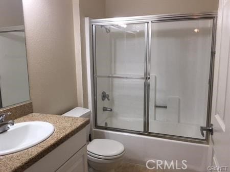 full bathroom featuring bath / shower combo with glass door, vanity, and toilet