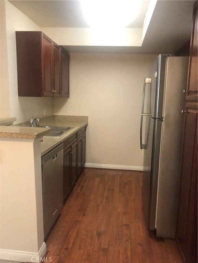 kitchen featuring appliances with stainless steel finishes, dark hardwood / wood-style flooring, sink, and light stone counters