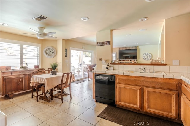 kitchen featuring black dishwasher, ceiling fan, tile counters, and plenty of natural light