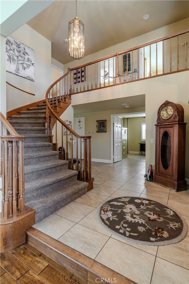 tiled entrance foyer featuring a towering ceiling and a chandelier