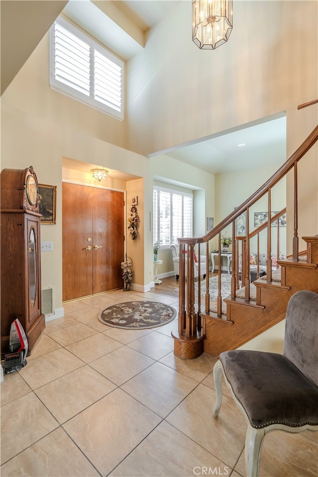 tiled foyer entrance featuring a chandelier and a high ceiling