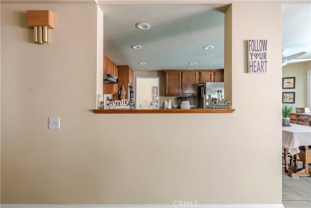 kitchen with stainless steel fridge, kitchen peninsula, and light tile patterned flooring