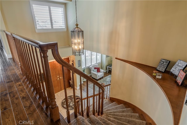 stairway with hardwood / wood-style flooring and a notable chandelier