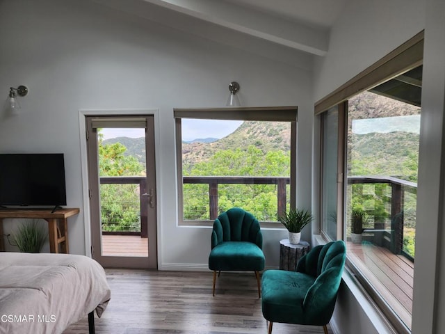 bedroom featuring lofted ceiling with beams, a mountain view, hardwood / wood-style flooring, and access to exterior