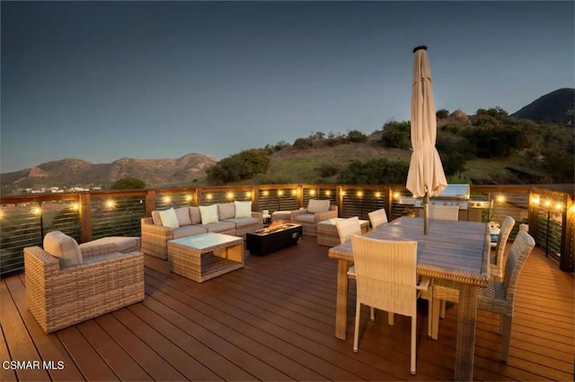 deck at dusk featuring an outdoor living space and a mountain view