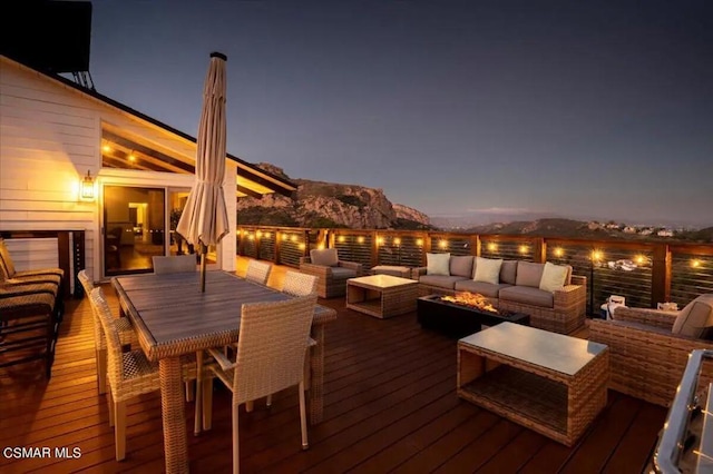 deck at dusk with outdoor lounge area and a mountain view