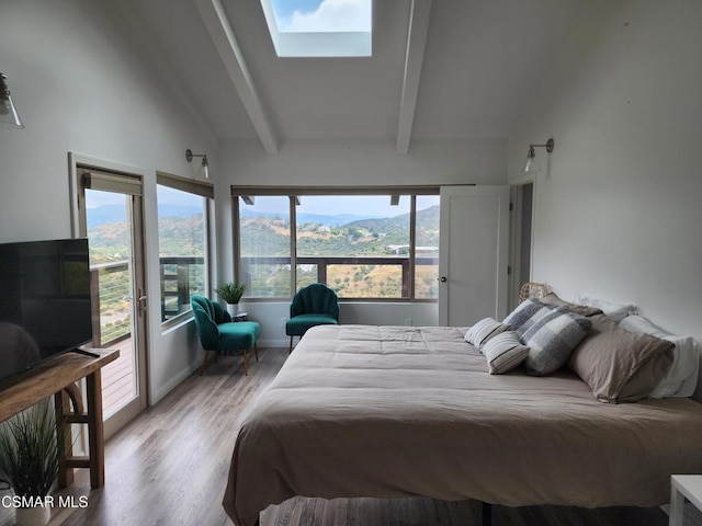 bedroom featuring light wood-type flooring, a mountain view, and vaulted ceiling with skylight