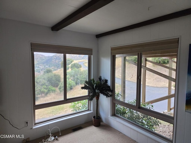 sunroom featuring beamed ceiling and a wealth of natural light