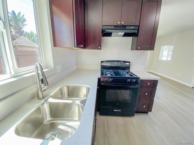 kitchen with light stone countertops, light hardwood / wood-style floors, black range with gas cooktop, and sink