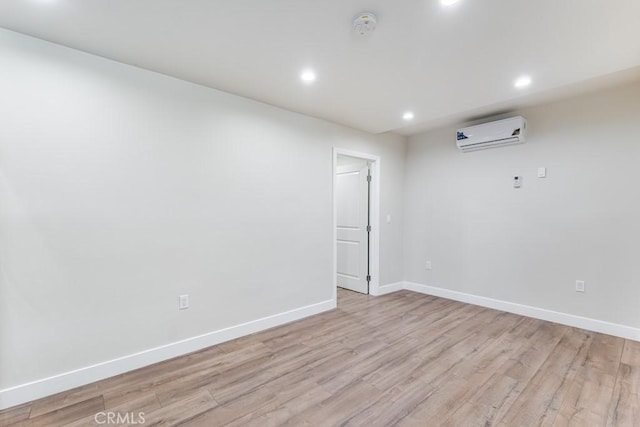 unfurnished room featuring a wall mounted air conditioner and light hardwood / wood-style floors