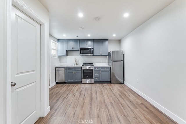 kitchen with appliances with stainless steel finishes, light hardwood / wood-style floors, gray cabinets, and sink