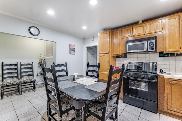 kitchen with tile counters, light tile patterned flooring, black range with gas stovetop, and backsplash