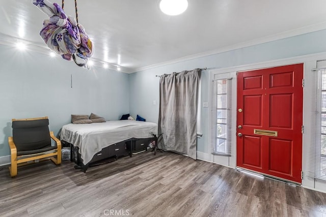 bedroom with hardwood / wood-style flooring, ornamental molding, and multiple windows