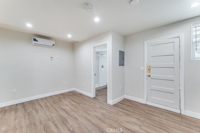 interior space with an AC wall unit, electric panel, and light hardwood / wood-style floors