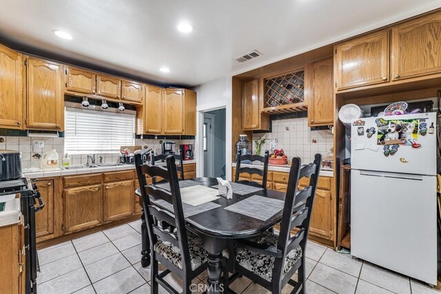 kitchen featuring tile counters, black stove, light tile patterned floors, and white refrigerator