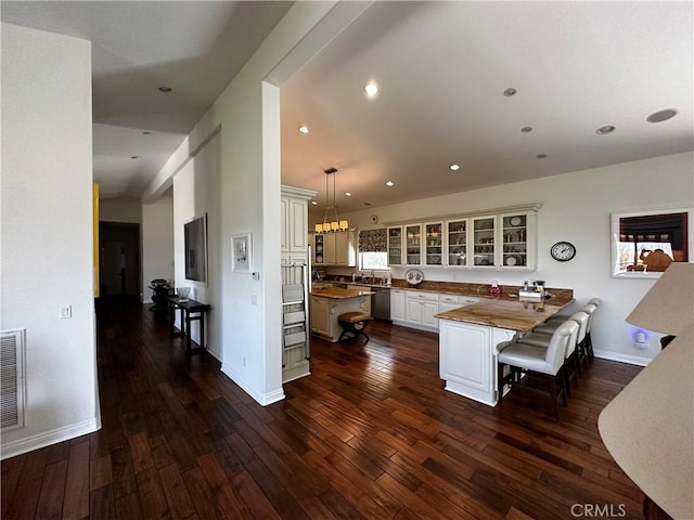 kitchen featuring pendant lighting, dishwasher, white cabinetry, dark hardwood / wood-style flooring, and kitchen peninsula