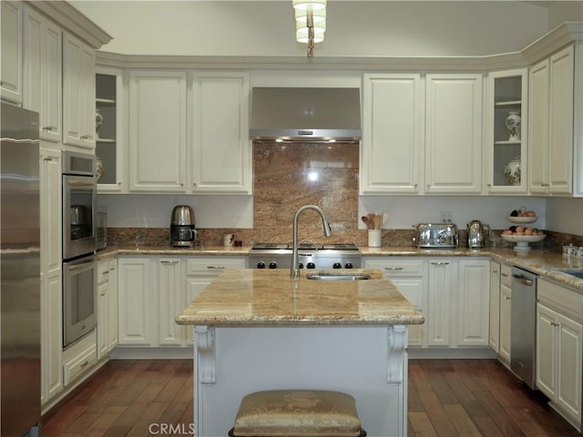 kitchen featuring a center island with sink, white cabinetry, light stone countertops, stainless steel appliances, and dark hardwood / wood-style flooring