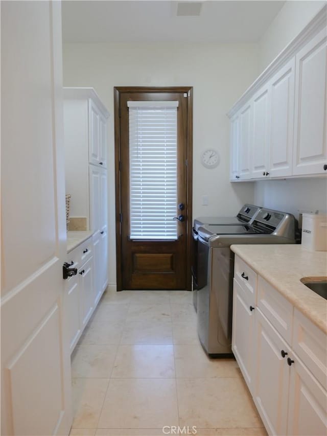 laundry area with cabinets, light tile patterned floors, and independent washer and dryer