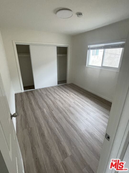 unfurnished bedroom with a closet and hardwood / wood-style floors