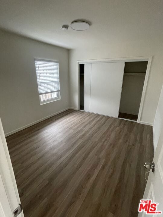 unfurnished bedroom featuring dark hardwood / wood-style floors and a closet