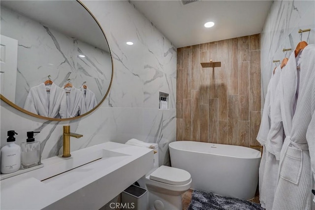 bathroom featuring a bathtub, toilet, and tile walls