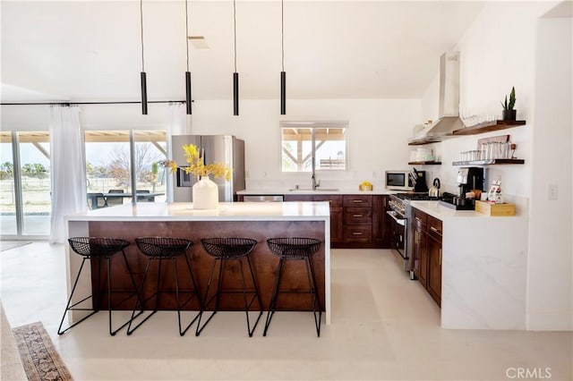 kitchen with sink, stainless steel appliances, pendant lighting, extractor fan, and a kitchen bar