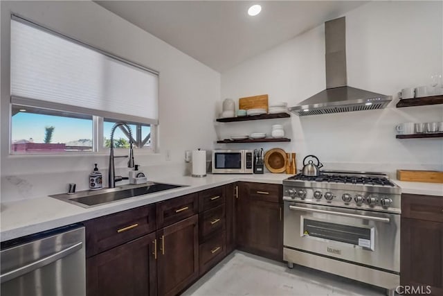 kitchen with lofted ceiling, sink, wall chimney exhaust hood, appliances with stainless steel finishes, and dark brown cabinetry