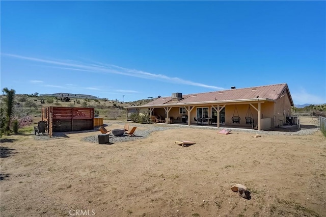 rear view of house with a patio area, central air condition unit, and an outdoor fire pit