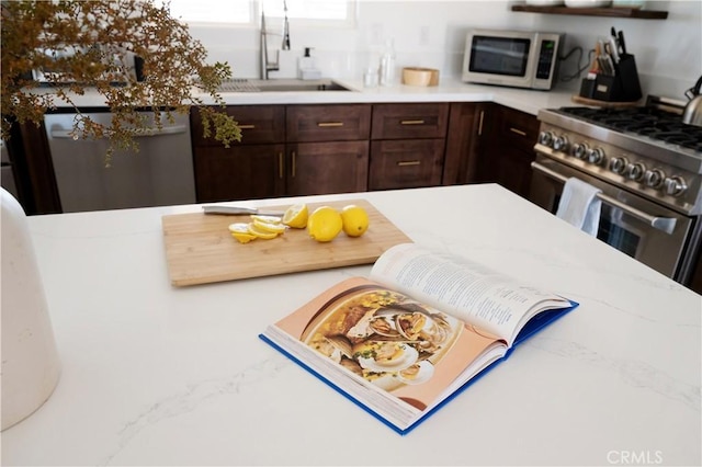 interior space featuring dark brown cabinetry, light stone counters, sink, and white appliances