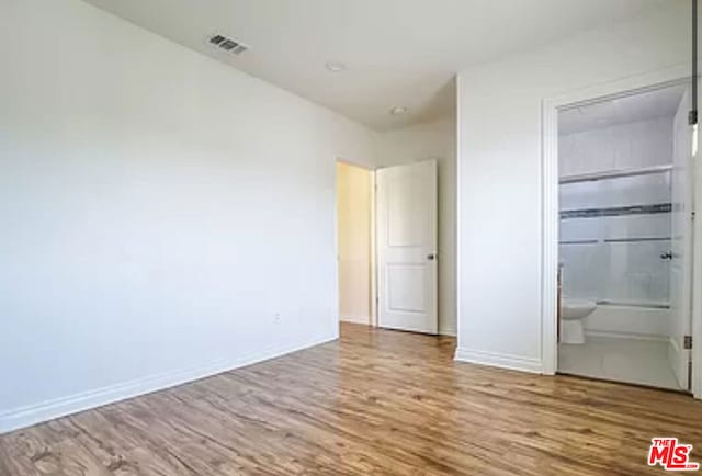 unfurnished bedroom featuring connected bathroom and light hardwood / wood-style floors