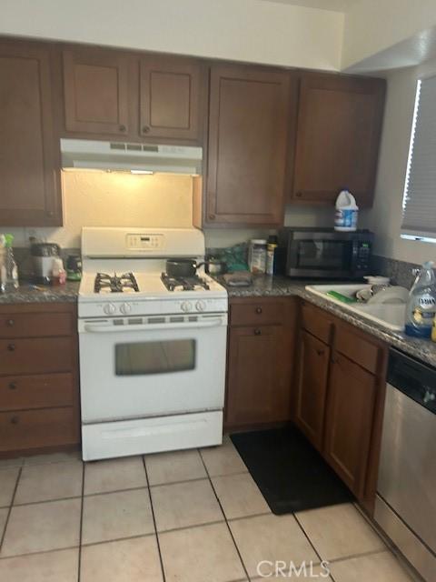 kitchen featuring stainless steel appliances, ventilation hood, sink, and light tile floors