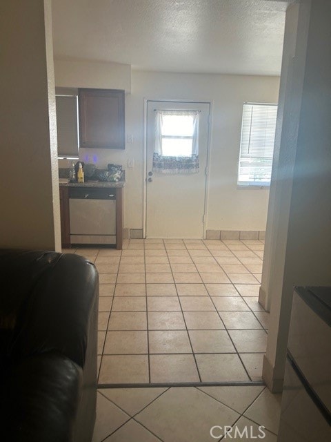 interior space with a textured ceiling, light tile flooring, and white dishwasher