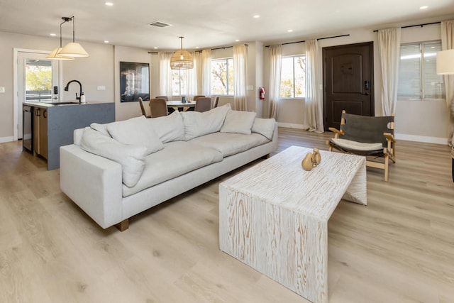 living room with light hardwood / wood-style floors, sink, and a wealth of natural light