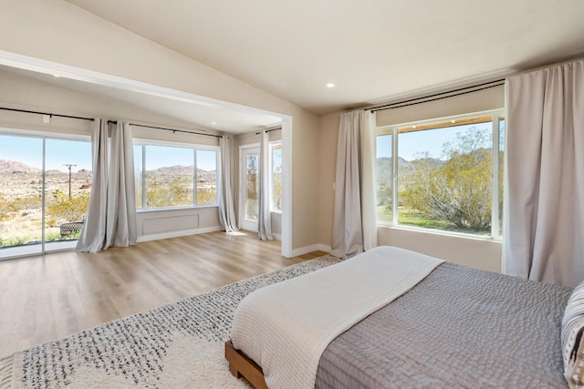 bedroom featuring vaulted ceiling, light hardwood / wood-style floors, a mountain view, and access to outside