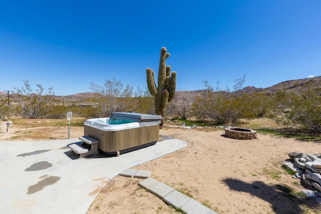 view of yard with a hot tub, a mountain view, a patio, and an outdoor fire pit