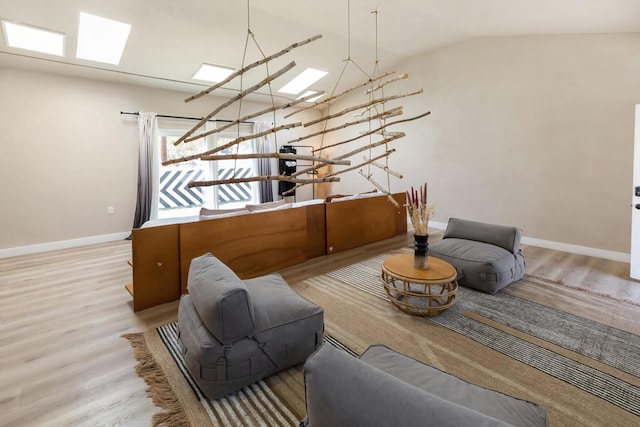 living room with vaulted ceiling with skylight and light hardwood / wood-style floors