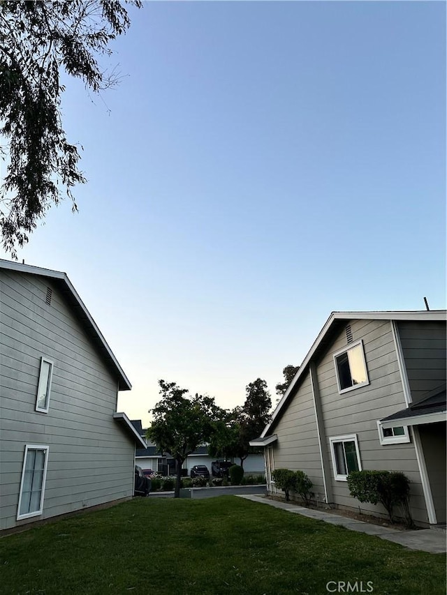 property exterior at dusk featuring a lawn