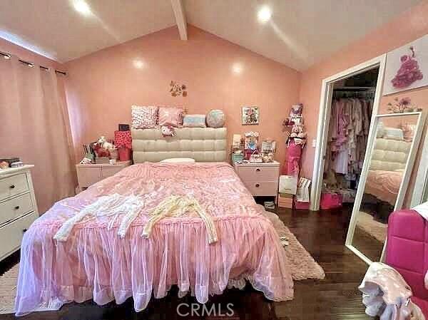 bedroom featuring dark hardwood / wood-style floors, a closet, and vaulted ceiling with beams