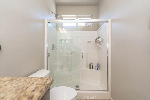 bathroom featuring a shower with shower door and toilet